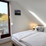 Bedroom with double bed, window to balcony, and wall picture.