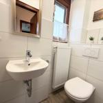 Bathroom with sink, mirror, toilet, and window.