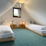 Two beds with nightstands and lamps under a skylight window.