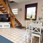 Living and dining area with wooden stairs, TV, and table with chairs.
