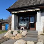 House with terrace, seating area, and stone beds in the front garden.