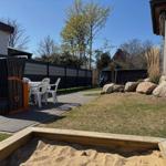 Backyard with sandbox, patio, lawn, and rocks.