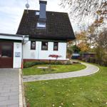 House with garden, stone path, and red tree. Garage and satellite dish.