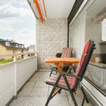 Terrasse mit Tisch, zwei Stühlen und Blick auf Wohngebiet.
