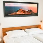 Schlafzimmer mit Doppelbett, Holz-Kopfteil und Wandbild an der Wand.