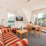 Wohn- und Essbereich mit Sofa, Tisch und Blick auf Balkon.