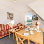 Wohn- und Essbereich mit Sofa, Tisch und Fenster. Wandbild und TV montiert.