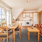 Wohnküche mit Essbereich und Balkonblick. Sofa, Tisch und Küchenschränke sichtbar.