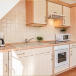 Küche mit weißen Schränken, Edelstahlspüle und integriertem Herd.