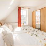 Schlafzimmer mit Dachschräge, Bett, Kleiderschrank und Fenster mit roter Vorhang.