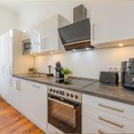 Moderne Küche mit weißen Schränken, Edelstahlgeräten und dunklem Arbeitsplatte.