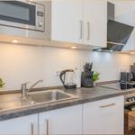 Küche mit Spüle, Herd, Dunstabzug und Mikrowelle.