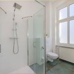 Dusche mit Glaswand, Toilette und Fenster mit Heizkörper.