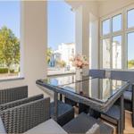 Terrasse mit Sitzgruppe, Tisch und Blick auf Straße und Gebäude.