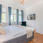 Schlafzimmer mit Doppelbett, Fenstern, Spiegelschrank und Kronleuchter.