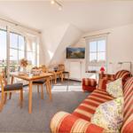 Wohn- und Essbereich mit Sofa, Tisch und Balkontür. Blick auf Terrasse.