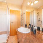 Badezimmer mit Dusche, Waschbecken und Spiegel.