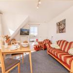 Wohn- und Essbereich mit Sofa, Stühlen und TV unter Dachschräge.