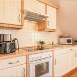 Küche mit weißen Schränken, Herd, Dunstabzug und Arbeitsfläche.