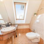 Badezimmer mit Waschbecken, Toilette und Dachfenster. Fliesenwand und Granitplatte.