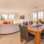 Großer Essbereich mit Holztisch und Stühlen. Wohnbereich mit Sofa und Fenstern.