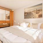 Schlafzimmer mit Bett, Kleiderschrank und Wandbild.