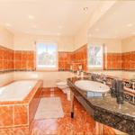 Bad mit Badewanne, Waschbecken und Toilette. Wand- und Bodenfliesen in warmen Tönen.