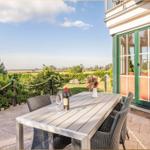 Terrasse mit Tisch und Stühlen, Blick auf grüne Landschaft.