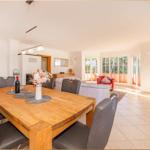 Esszimmer mit Holztisch und Stühlen. Wohnbereich mit Sofa und rotem Sessel.