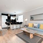 Wohnbereich mit Sofa, Couchtisch und Küchenzeile mit Barhockern.