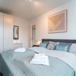 Schlafzimmer mit Bett, Nachttischen und Kleiderschrank. Auf dem Bett liegen Handtücher.