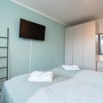 Schlafzimmer mit Bett, Fernseher, Kleiderschrank und Spiegel.