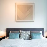 Schlafzimmer mit Bett, Nachttischen und Wandbild.