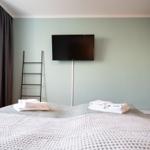 Schlafzimmer mit Bett, Fernseher und Fenster. Handtücher auf dem Bett.