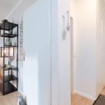 Eingangsbereich mit schwarzer Regalwand, Tür und Holzboden. Dekorative Elemente an der Wand.