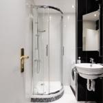 Badezimmer mit Duschkabine, Waschbecken und Waschmaschine.