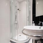 Badezimmer mit Dusche, Waschbecken und Heizung.