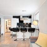 Moderne Küche mit Barhocker und Wohnbereich mit Sofa und Beistelltisch.