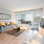 Wohnzimmer mit Sofa, Couchtisch und TV. Durchgang zur Terrasse mit Tisch und Stühlen.