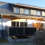 Moderne Ferienwohnung mit Solaranlagen und Balkon. Außenbereich mit Holzverkleidung.