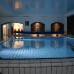 Innere Schwimmbad mit beleuchteten Fliesen und Statuen an der Wand.