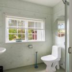 Badezimmer mit Toilette, Waschbecken und Fenster mit Blick nach draußen.