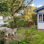 Haus mit Terrasse, Garten und Blick auf Wasser.