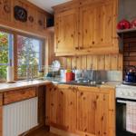 Küche mit Holzmöbeln, Fenster und Herd. Aufbewahrung und Arbeitsfläche.