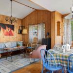 Wohn- und Essbereich mit Holzwand, Sofa, Tisch und Stühlen.