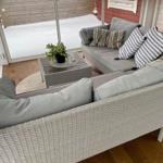 Terrassenbereich mit grauem Rattan-Sofa und Tisch. Hintergrund: Schnee und Holzwand.