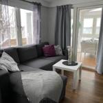 Ein Wohnzimmer mit grauem Sofa, weißem Tisch und großen Fenstern.