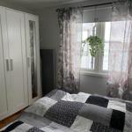 Schlafzimmer mit Bett, Kleiderschrank und Fenster mit Vorhängen.