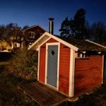 Roter Holzaufbau mit blauer Tür und Schornstein im Freien.