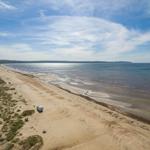 Strand mit Wohnwagen, Sand und Meer unter blauem Himmel